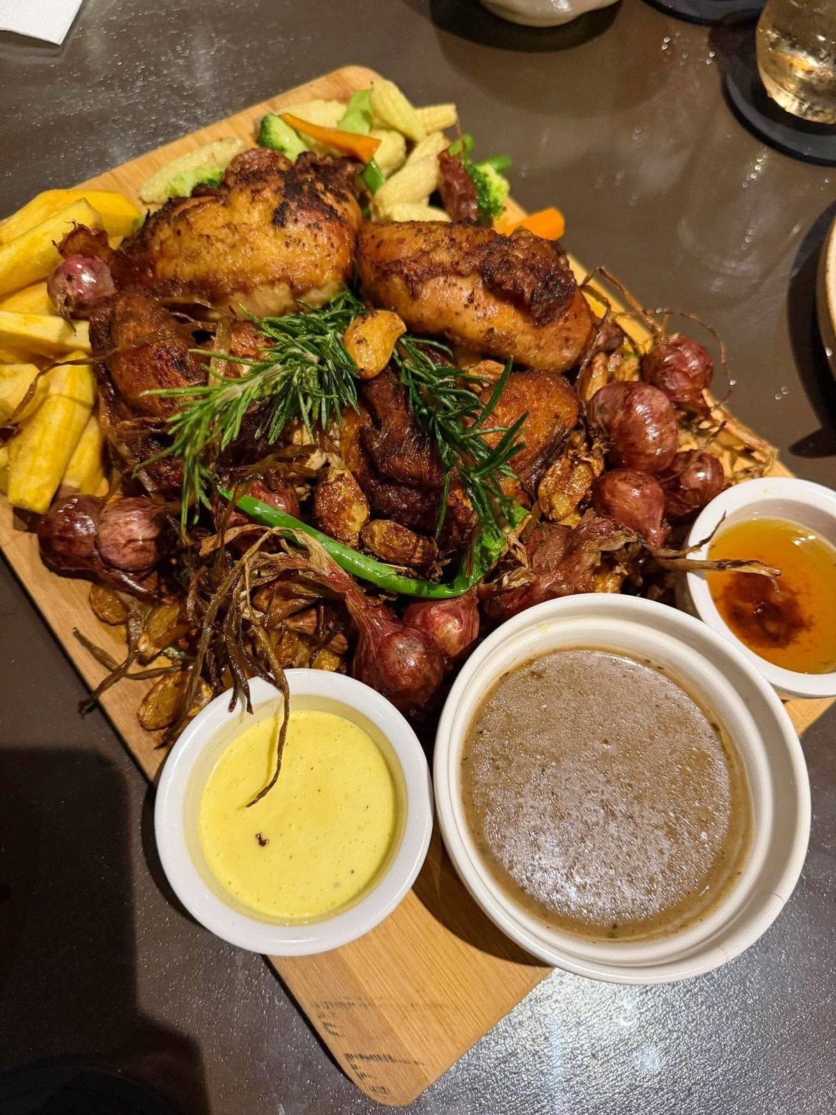 Roast chicken with fries and sausage on a board with two sauces
