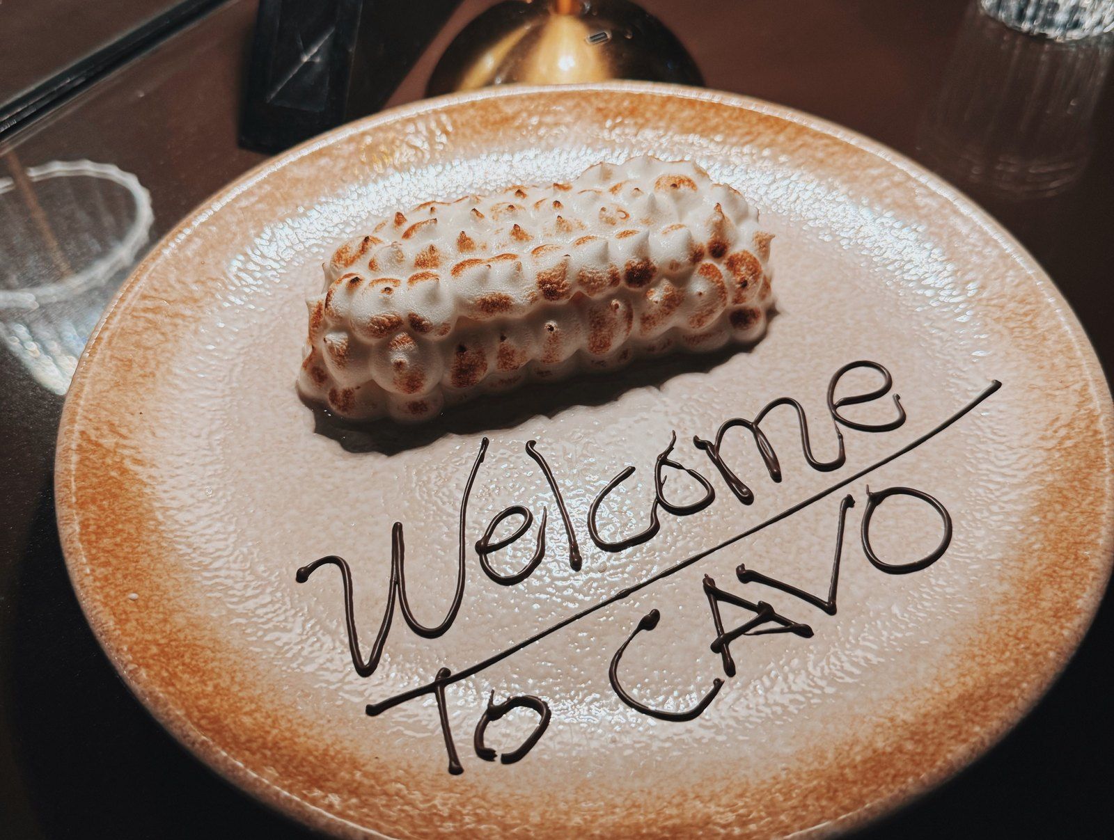 A dessert on a plate with Welcome to CAVO written in chocolate