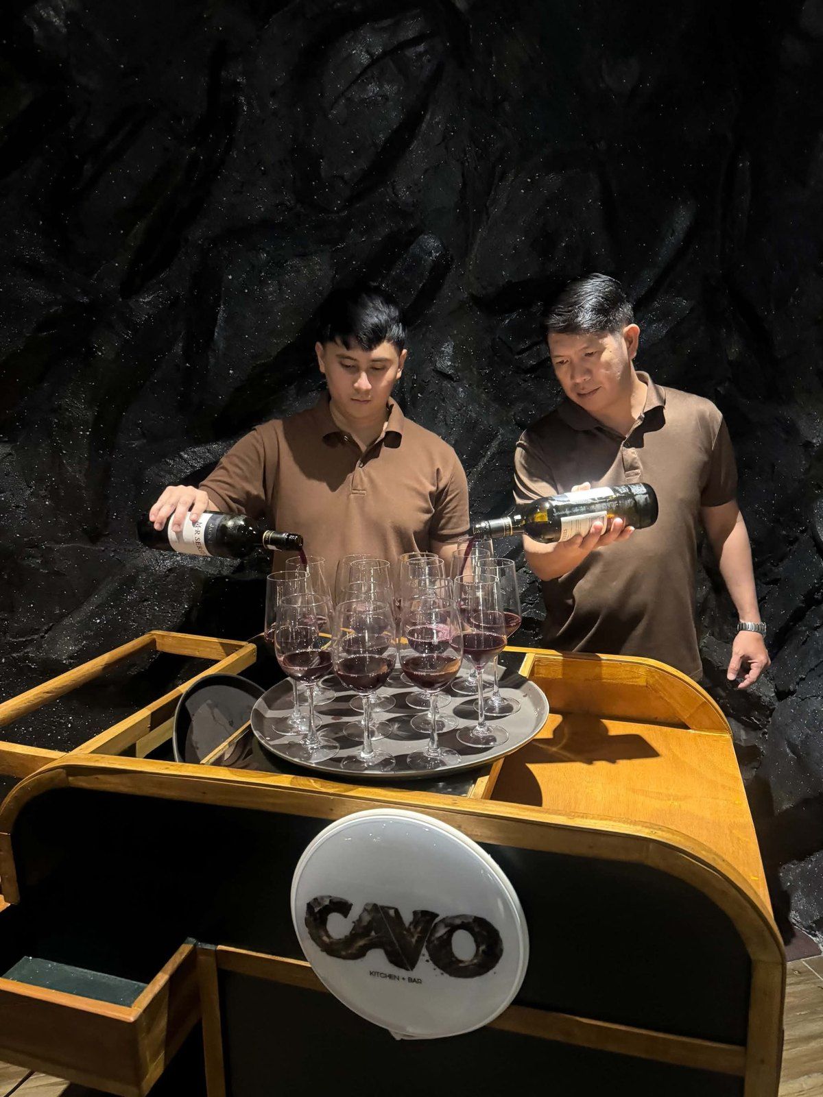 Two Cavo staff pouring red wine at the mobile bar