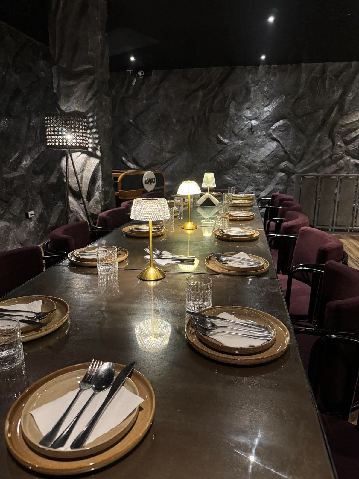 A long table set for a private party on the upper floor, with gold chargers and candle lamps
