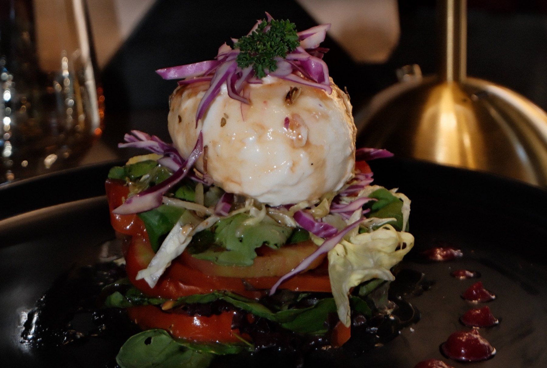 Burrata on sliced tomatoes with greens and basil