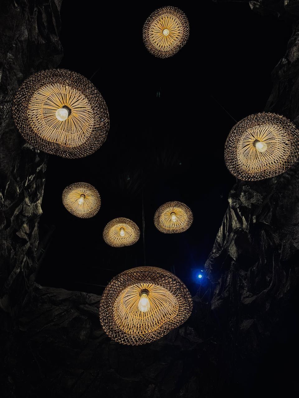 Woven pendant lamps glowing against the dark rock ceiling