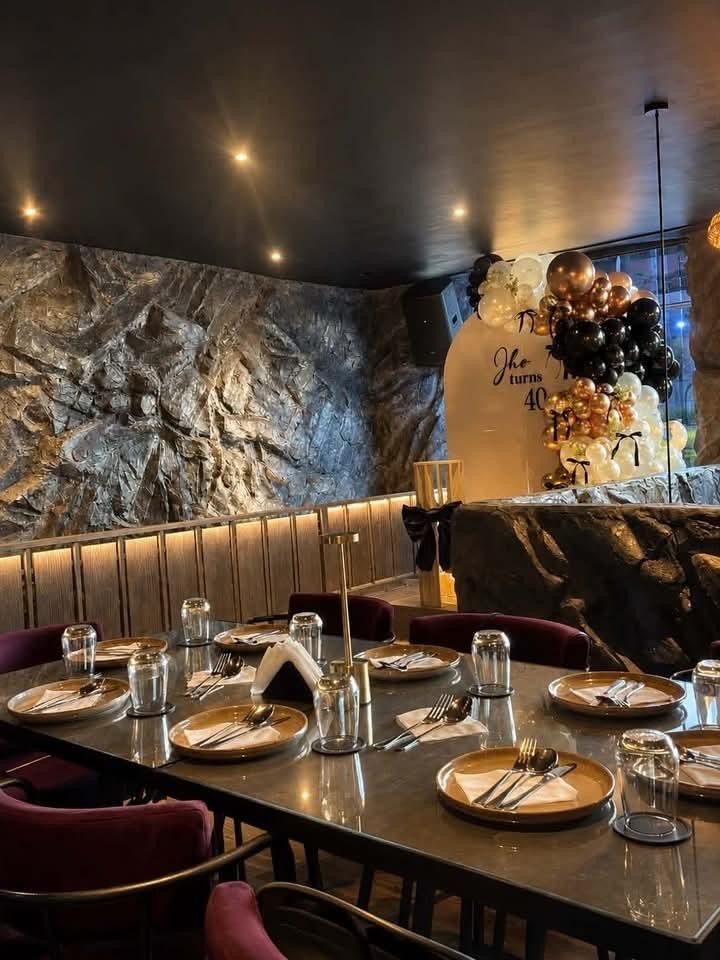 The dining room set for dinner: stone walls, warm lights and tables laid with glasses