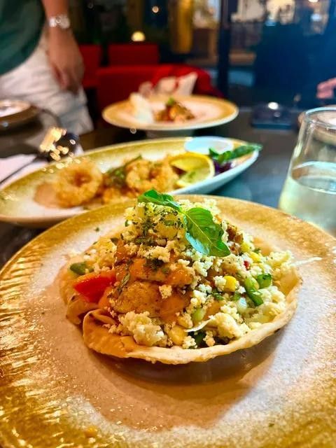 A table of shared plates with a crispy tortilla bowl in front