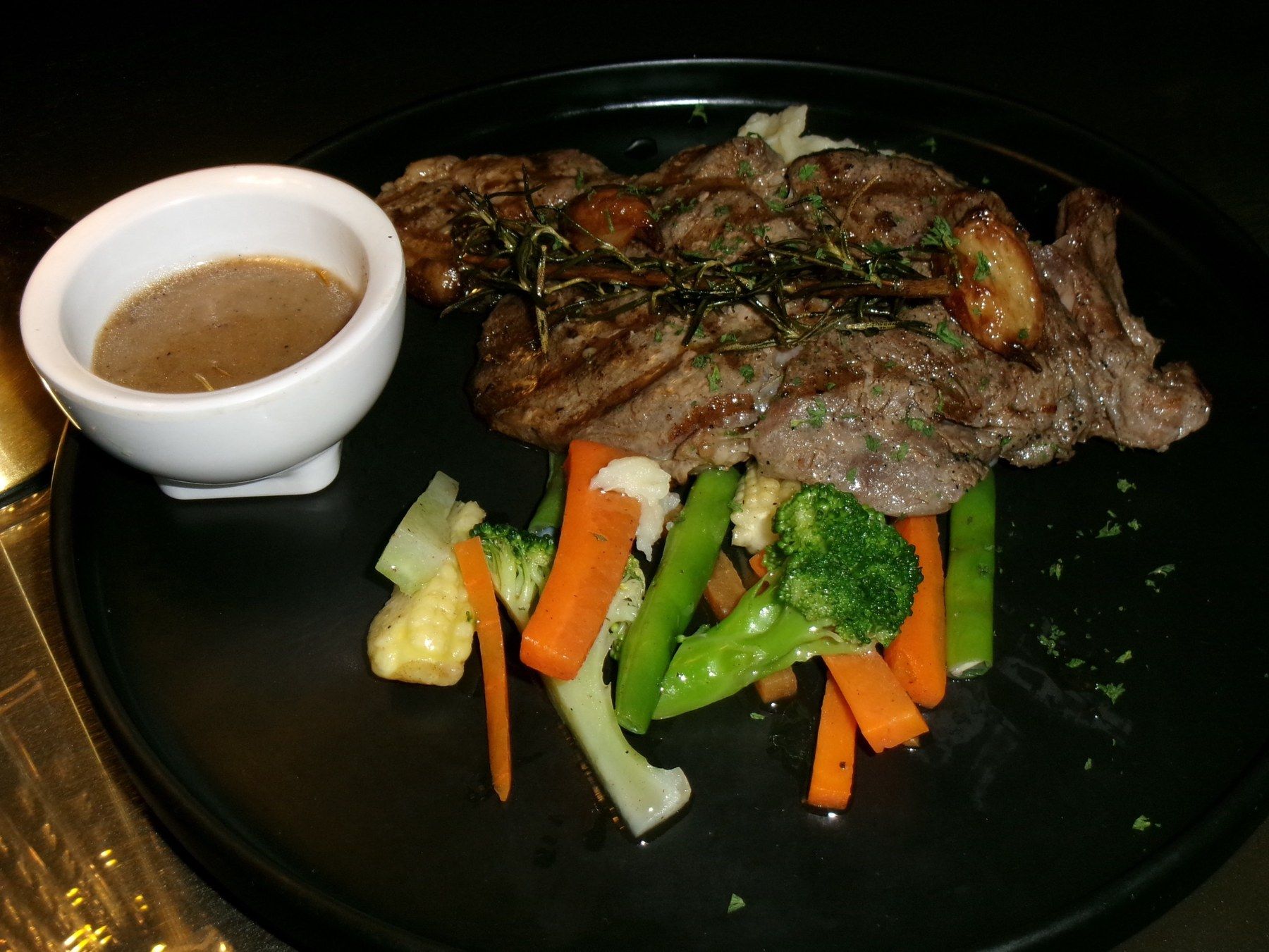 Sliced seared steak with herbs, grilled vegetables and a cup of gravy
